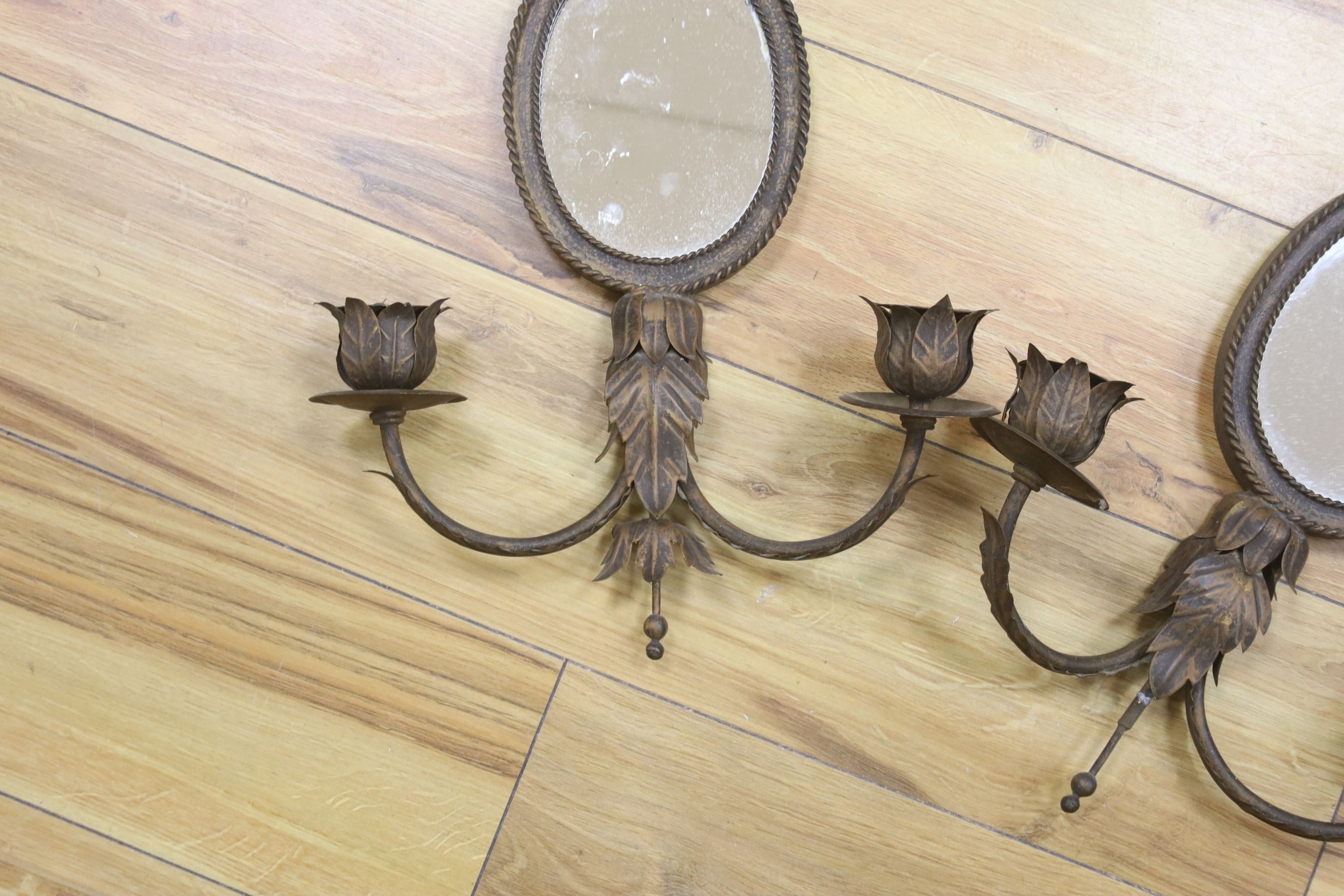 A pair of wrought copper oval two branch girandole mirrors, length 56cm